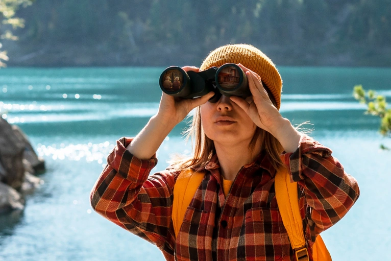 Frau mit Fernglas in der Natur